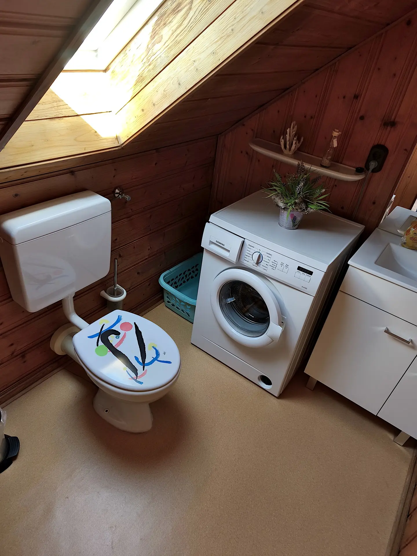 kleines Badezimmer im Obergeschoss mit Waschmaschine, Waschbecken, Spiegel und WC